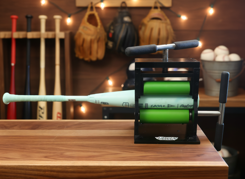 Bat rolling machine with a composite bat in the green rollers